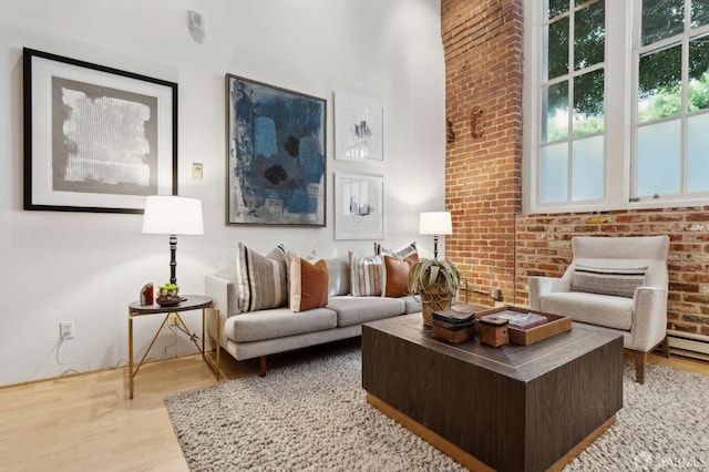 living room featuring brick wall and wood finished floors