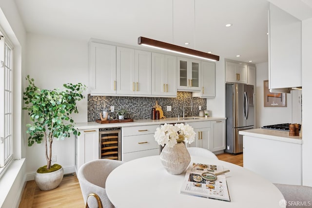 246 Ralston St, San Francisco, CA 94132 - kitchen with appliances with stainless steel finishes, wine cooler, light wood-style floors, backsplash, and light countertops