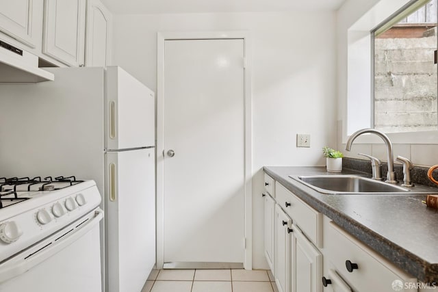 246 Ralston St, San Francisco, CA 94132 - kitchen with under cabinet range hood, white gas range, dark countertops, light tile patterned flooring, and white cabinets