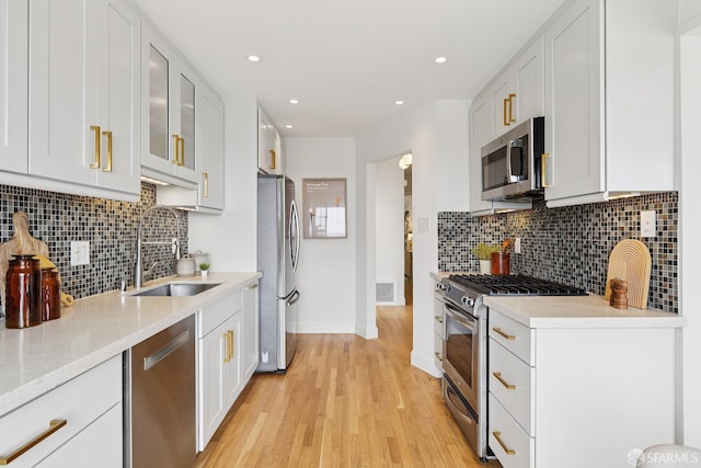 246 Ralston St, San Francisco, CA 94132 - kitchen featuring appliances with stainless steel finishes, light wood-style flooring, backsplash, white cabinets, and recessed lighting