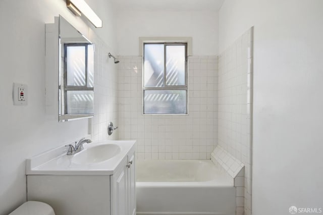 full bathroom with vanity, tiled shower / bath combo, and toilet