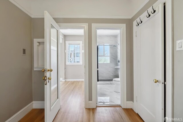 doorway to outside featuring crown molding and light hardwood / wood-style flooring