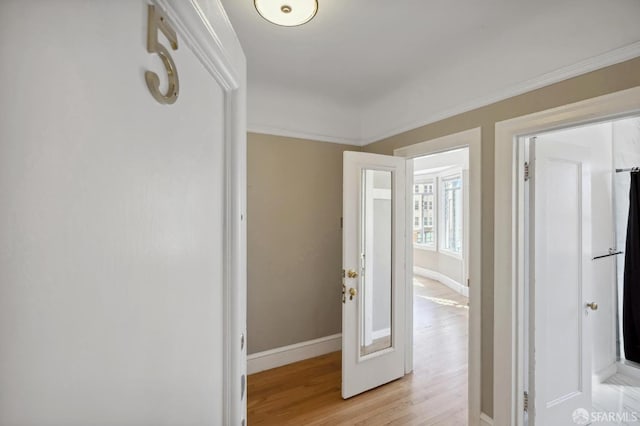 hall with light hardwood / wood-style floors and crown molding