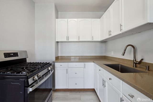 kitchen with white cabinetry, stone counters, stainless steel range with gas cooktop, and sink