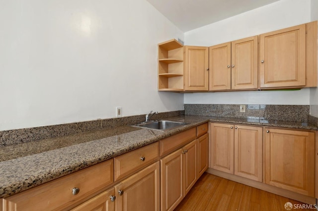 kitchen featuring light brown cabinets, sink, stone counters, and light wood-type flooring