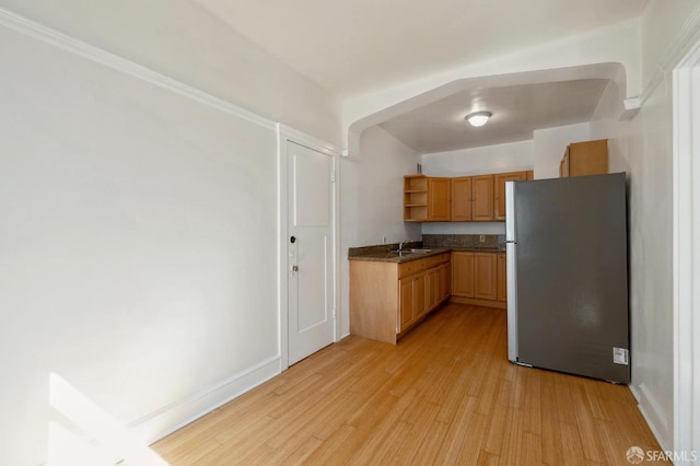 kitchen with sink, crown molding, light hardwood / wood-style flooring, and stainless steel fridge