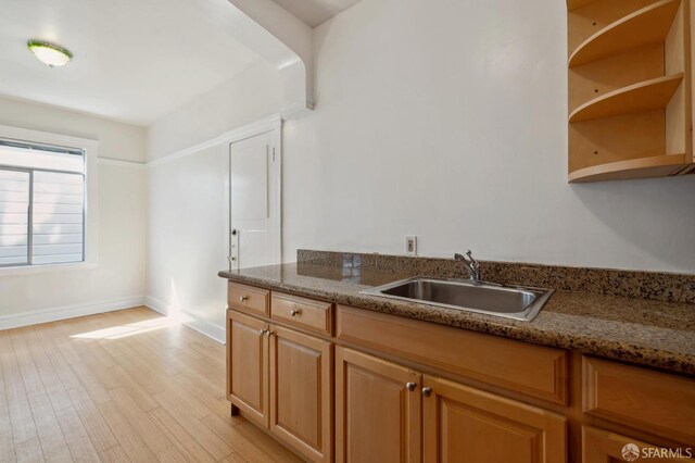 kitchen featuring sink, stone countertops, and light wood-type flooring