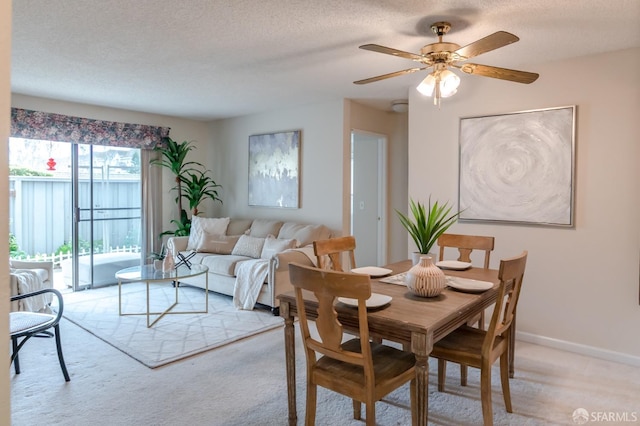 dining area with ceiling fan, light colored carpet, and a textured ceiling