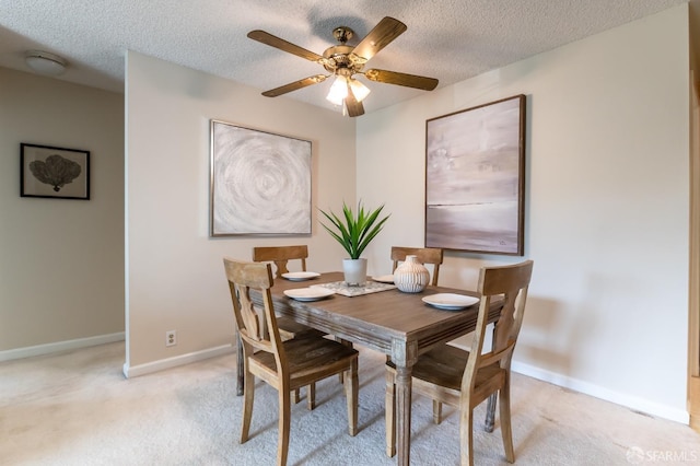 dining area with a textured ceiling, light carpet, and ceiling fan