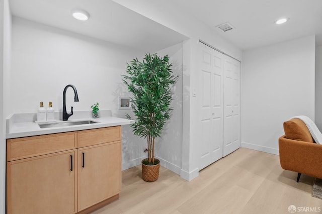 bar featuring a sink, light wood-type flooring, recessed lighting, and baseboards