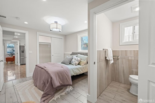 74 Crane St, San Francisco, CA 94124 - bedroom featuring stainless steel fridge with ice dispenser, recessed lighting, a closet, a wainscoted wall, and wood finish floors