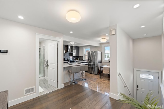 74 Crane St, San Francisco, CA 94124 - kitchen featuring stainless steel fridge, backsplash, a breakfast bar area, light wood finished floors, and recessed lighting