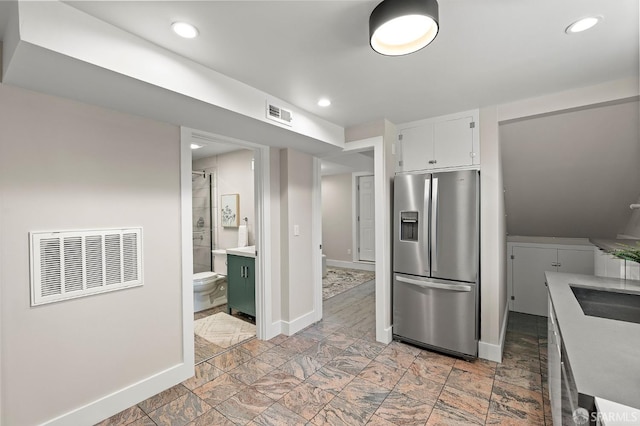 74 Crane St, San Francisco, CA 94124 - kitchen with stainless steel fridge with ice dispenser, baseboards, white cabinets, light countertops, and light stone finish flooring