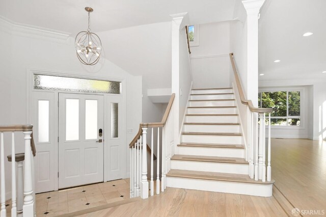 foyer featuring crown molding, light hardwood / wood-style floors, and an inviting chandelier