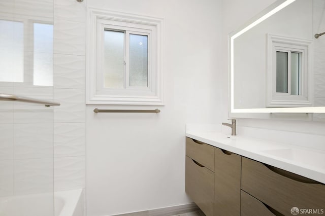 bathroom with vanity, hardwood / wood-style flooring, and tiled shower / bath