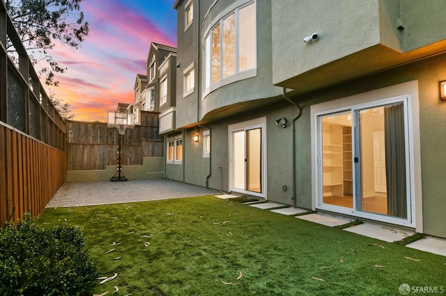 back house at dusk with a yard and a patio area