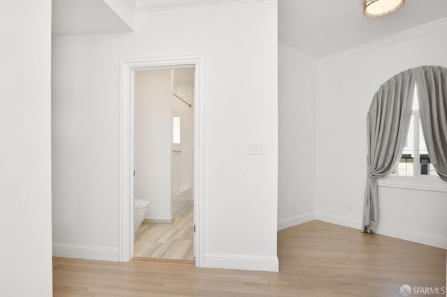 unfurnished bedroom featuring light wood-type flooring, ornamental molding, and connected bathroom