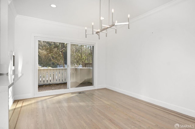 unfurnished dining area with light wood-type flooring, ornamental molding, and a chandelier