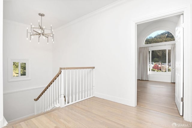 interior space featuring an inviting chandelier, ornamental molding, and light wood-type flooring