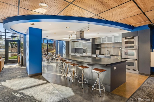 kitchen with a breakfast bar, concrete floors, island range hood, and a wall of windows