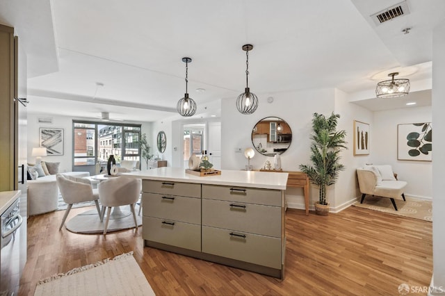 kitchen with pendant lighting, light wood-type flooring, stainless steel dishwasher, and a center island