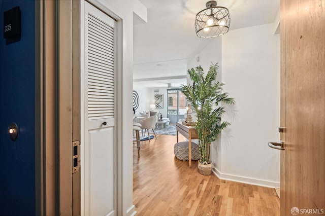 corridor featuring light wood-type flooring and a chandelier