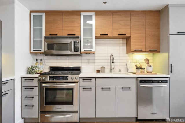 kitchen with white cabinets, stainless steel appliances, sink, and decorative backsplash