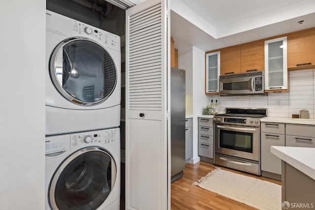 washroom featuring light hardwood / wood-style flooring and stacked washer / dryer