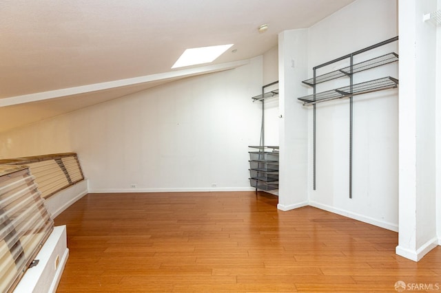 additional living space with hardwood / wood-style floors and a skylight