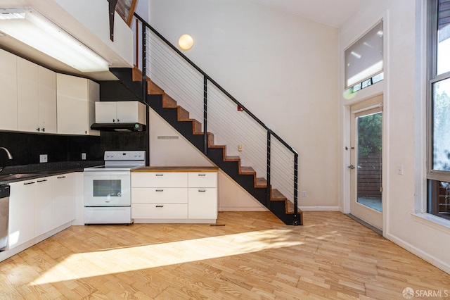 kitchen with electric range, white cabinets, sink, and light hardwood / wood-style flooring