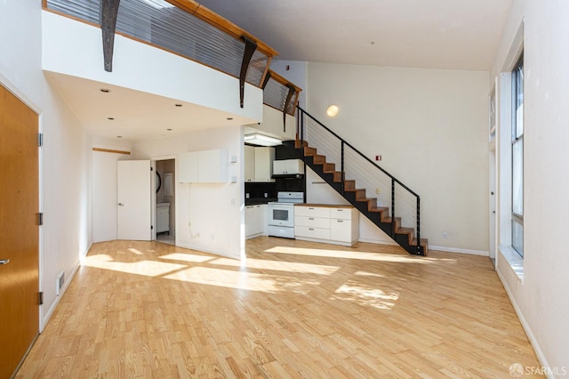 unfurnished living room featuring light hardwood / wood-style floors and a towering ceiling