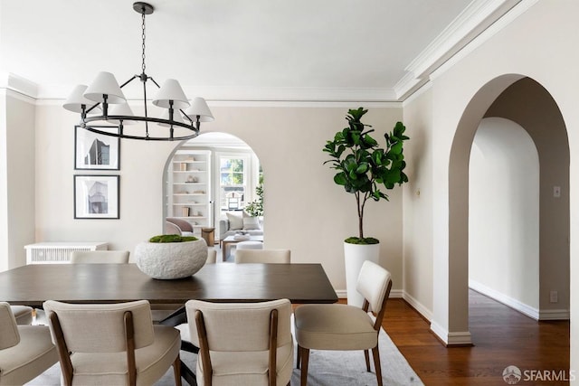 dining space featuring a chandelier, dark wood finished floors, arched walkways, ornamental molding, and baseboards