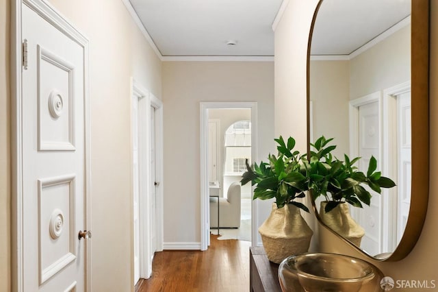 hall featuring wood finished floors, crown molding, and baseboards