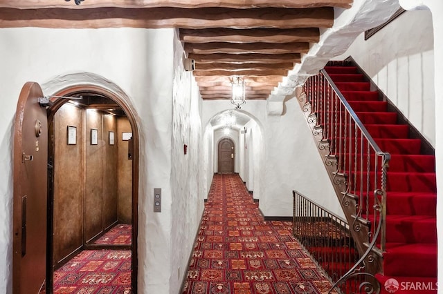 hallway featuring arched walkways, stairs, and elevator