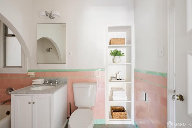 bathroom with tile walls, wainscoting, vanity, and toilet