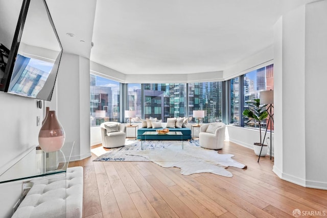 living area with a healthy amount of sunlight, a city view, and wood finished floors