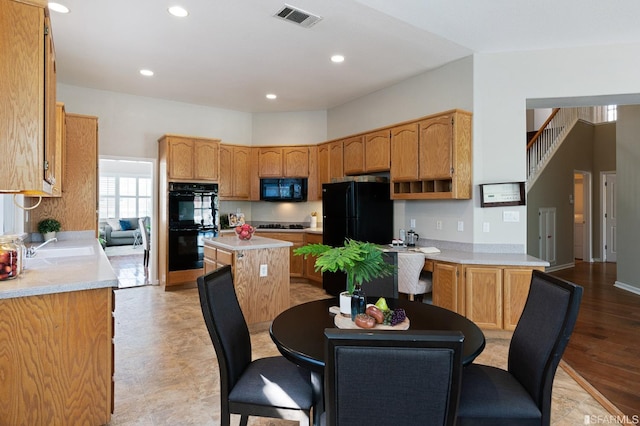 kitchen with a center island, sink, a kitchen breakfast bar, and black appliances