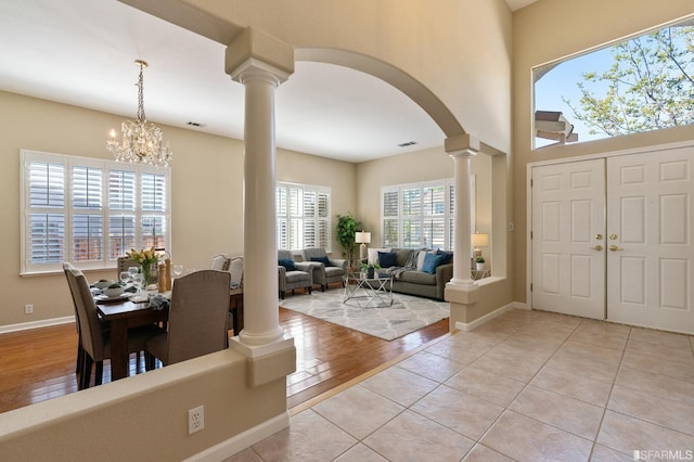 foyer entrance with a towering ceiling, decorative columns, and light tile patterned floors