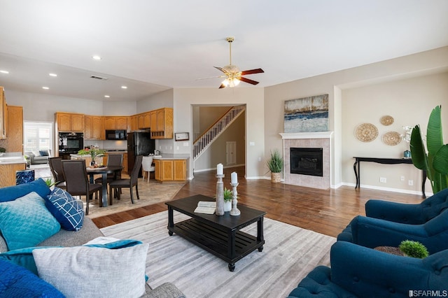 living room featuring ceiling fan, a fireplace, and light hardwood / wood-style floors