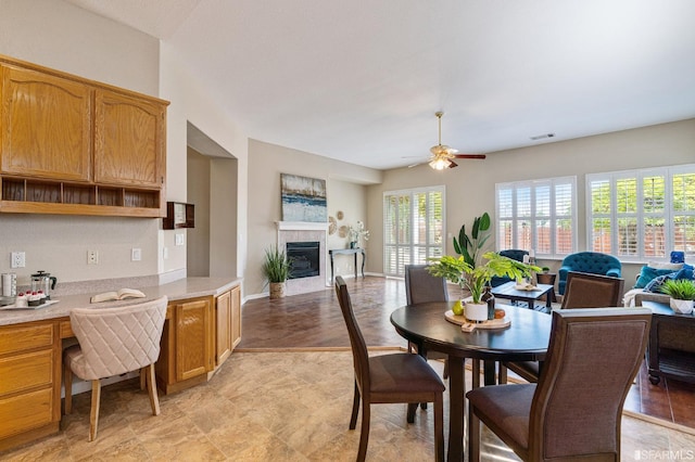 dining space featuring ceiling fan, a fireplace, and built in desk