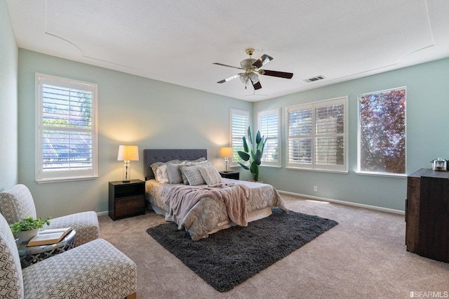 carpeted bedroom featuring multiple windows and ceiling fan