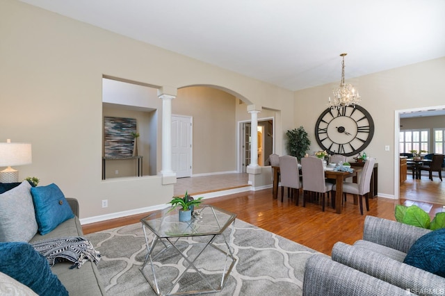 living room with a notable chandelier, hardwood / wood-style floors, and ornate columns