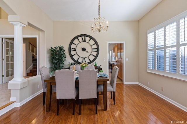 dining room with decorative columns, wood-type flooring, and a notable chandelier