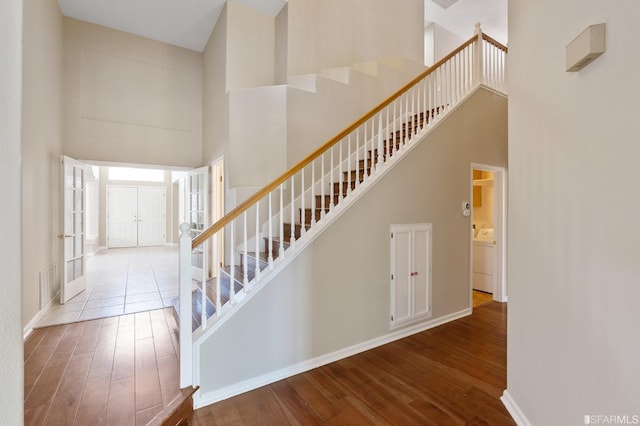 stairs with a towering ceiling, wood-type flooring, and washer / dryer