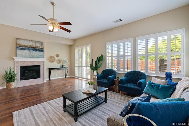 living room featuring hardwood / wood-style flooring, ceiling fan, and a tile fireplace