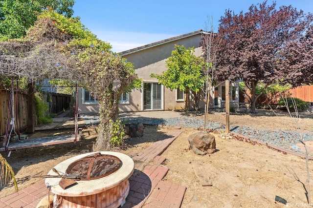 back of house with a fire pit and a patio