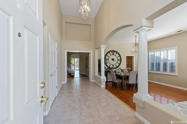 foyer with decorative columns, a healthy amount of sunlight, light tile patterned floors, and a chandelier