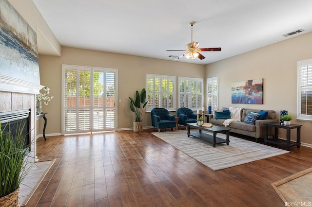 living room with a tiled fireplace, wood-type flooring, and ceiling fan