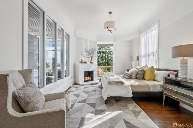 bedroom featuring wood finished floors, a fireplace, and access to outside