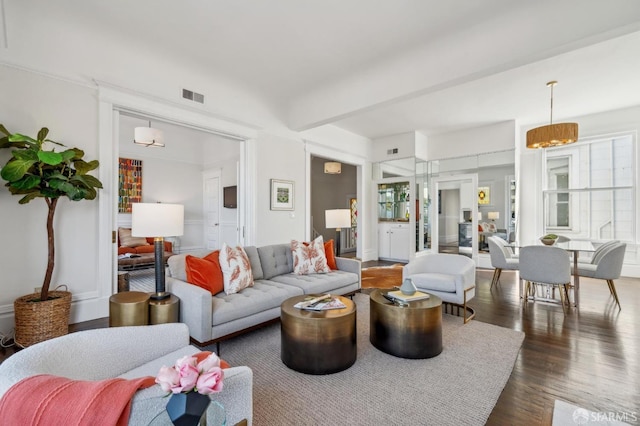 living area featuring beamed ceiling, wood finished floors, and visible vents